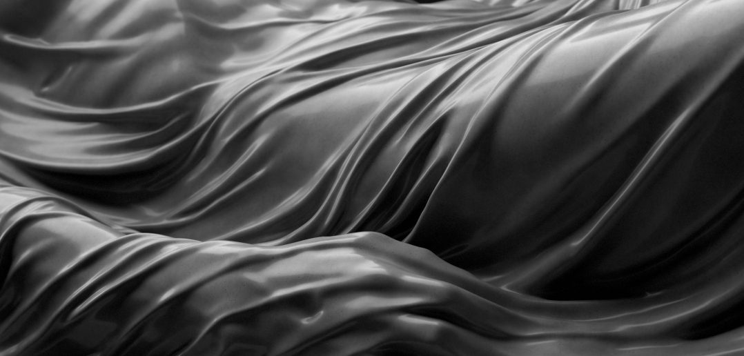 Close-up of wavy, shiny, metallic surface with intricate folds and reflections.