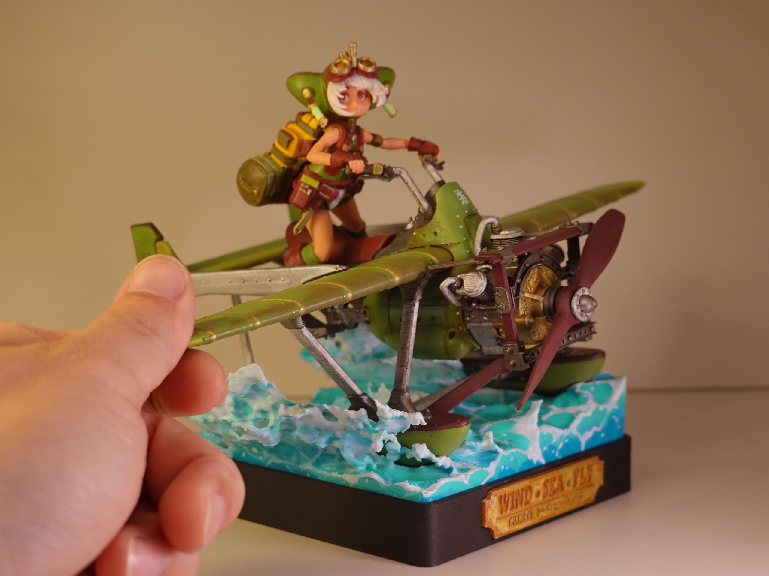 Miniature figure of a female pilot riding a green biplane over stylized waves.