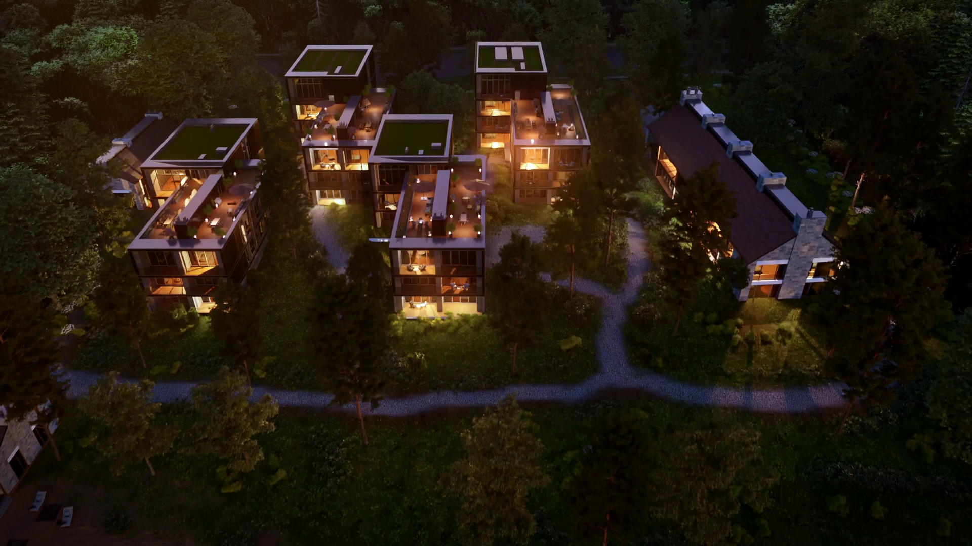 Aerial night view of modern houses with illuminated interiors surrounded by dense forest.