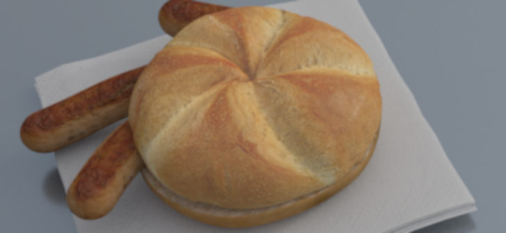 A golden-brown baked bread with a cross pattern sits on a white napkin, accompanied by two breadsticks.